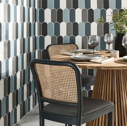 Table and chairs with multi-colour tiles on the walls near it