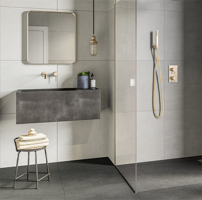 Shower room with grey tiles and gold taps and shower hose
