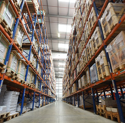 Warehouse with racking on either side full of pallets of stock.